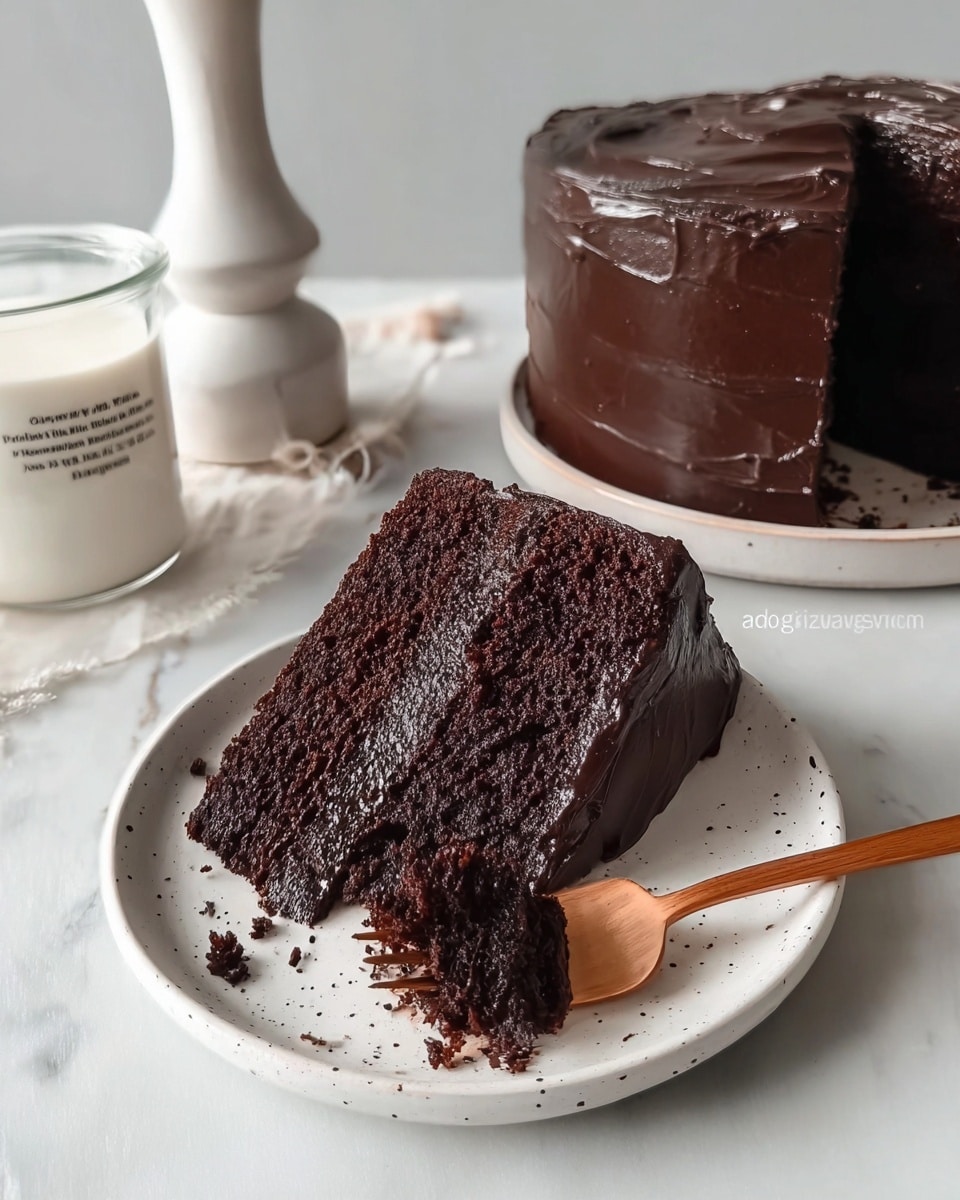 A thick slice of dark chocolate cake sits on a white plate with small black speckles around the rim. The cake has three visible layers: two moist, rich dark brown cake layers separated by a smooth, shiny dark chocolate frosting, which also covers the entire slice and the top and sides of the cake in the background. A wooden fork is placed on the slice, digging into the middle layer. The setting is a white marbled surface, with a white marbled candle holder and a clear glass of milk with writing on it nearby. Photo taken with an iphone --ar 4:5 --v 7