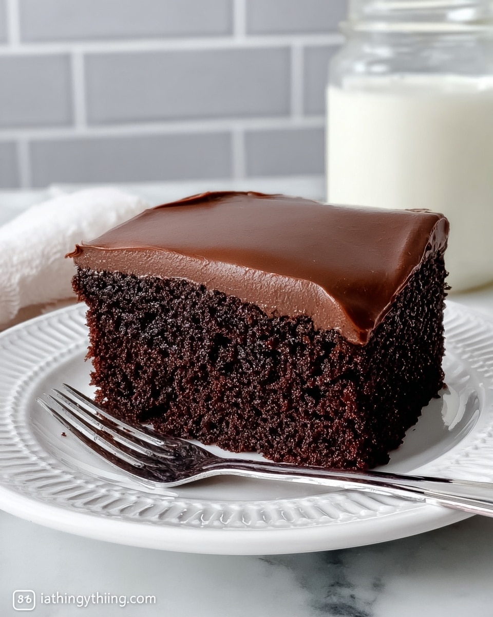 A single slice of chocolate cake sits centered on a white plate with intricate cut-out patterns around the edge. The cake has two thick layers: the bottom layer is a dark, moist chocolate sponge with a textured crumb, and the top layer is smooth, glossy milk chocolate frosting evenly spread and slightly rounded on top. The plate rests on a white marbled surface, and in the background to the right, there is a small glass jar of white milk. A silver fork leans against the plate's edge on the right side, slightly angled toward the cake. photo taken with an iphone --ar 4:5 --v 7