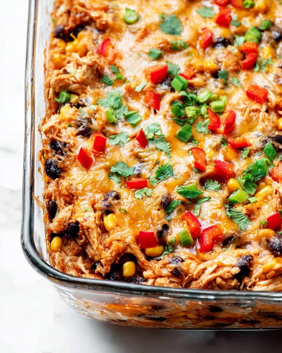 The image shows a close-up of a baked casserole in a clear glass dish set on a white marbled surface. The dish is filled with one thick layer of mixed ingredients including shredded chicken, melted cheese, black beans, corn, and diced red bell peppers, all warmly blended together with a slightly browned, melted cheese texture on top. Garnishes of chopped green onions and fresh cilantro leaves are scattered evenly across the top, adding bright green color and fresh texture contrasts. Photo taken with an iphone --ar 4:5 --v 7