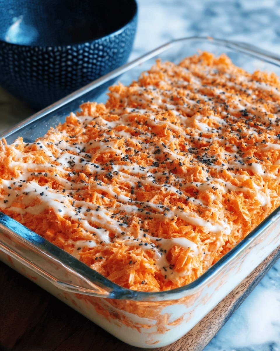 A clear rectangular glass dish holds two large portions of a creamy baked casserole with a golden, slightly crispy top. The surface is textured with streaks of orange and white sauce, swirled together with a drizzle of a lighter cream sauce forming thin stripes across the top. Black and red pepper flakes are sprinkled over both portions, adding specks of dark color. The dish is placed on a white marbled surface, with a glimpse of a dark blue cloth in the background. Photo taken with an iphone --ar 4:5 --v 7
