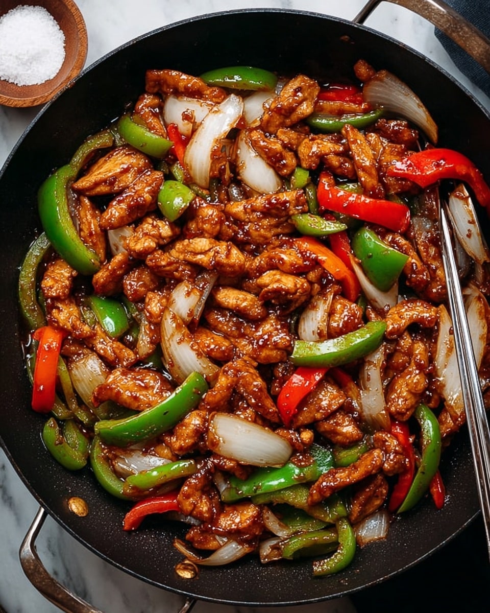 This image shows a black pan filled with a stir-fry dish. It has three main layers: first, pieces of cooked chicken that are brown and glazed, spread all over. Second, there are thick slices of onions that are white and slightly translucent mixed evenly. Third, bright red and green bell pepper pieces cut into strips are scattered throughout the dish, adding color contrast. The pan is on a white marbled surface. A small wooden bowl with white coarse salt is on the top left, and a pair of silver chopsticks rest inside the pan on the bottom left. photo taken with an iphone --ar 4:5 --v 7
